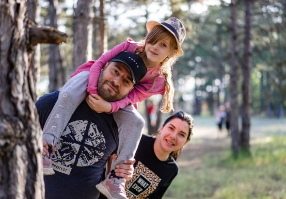 A joyful family enjoying a playful day in a sunlit forest park, capturing the essence of togetherness.